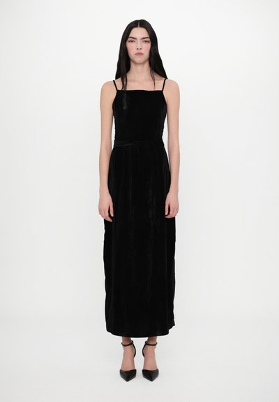 Vestido de terciopelo negro con tirantes finos, escote cuadrado y una silueta larga y fluida. Presenta una cintura ceñida que proporciona definición.
