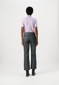 Gai violet īsām piedurknēm top, savienots ar augsto jostasvietu tumši pelēkiem, platām biksēm. Melni potīšu zābaki ar masīlu papēdi.