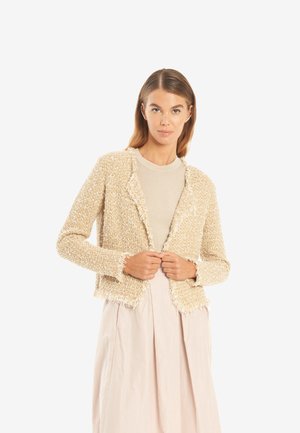 Beige strukturierte Jacke mit fransigen Kanten. Hergestellt aus einem gewebten Stoff, hat sie einen leicht verkürzten Schnitt und ein lässiges, offenes Design.
