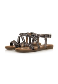 Sandalias trenzadas de color gris metálico con suela plana marrón. Presentan un cierre de hebilla y un diseño de punta abierta para mayor transpirabilidad.