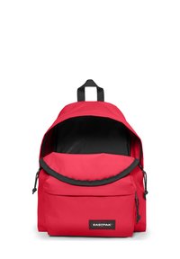 Mochila de tela roja con interior negro, parte superior redondeada, cierre de cordón y un bolsillo frontal con cremallera. Presenta el logo de Eastpak en la parte delantera.