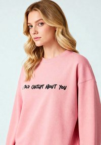 Felpa rosa con scollo rotondo e maniche lunghe, con testo nero ricamato che legge "HO PARLATO DI TE A CHATGPT."