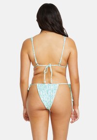 Bikini bleu clair avec un motif floral. Présente des bretelles fines ajustables, une fermeture à nouer à l'arrière et des nœuds sur le côté du bas.