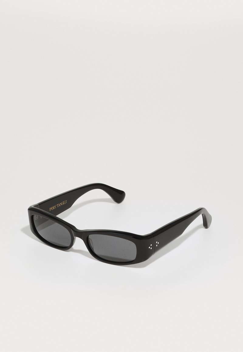 Óculos de sol pretos com um formato retangular. Lentes escuras sólidas, armação brilhante e pequenos acentos decorativos nas hastes. Nome da marca gravado.