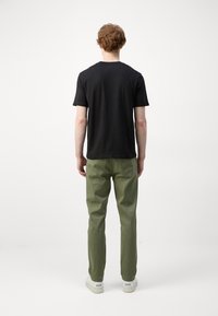Zwarte crew-neck t-shirt gecombineerd met olijfgroene broek. Het shirt heeft korte mouwen, terwijl de broek een rechte snit heeft met een gladde textuur.