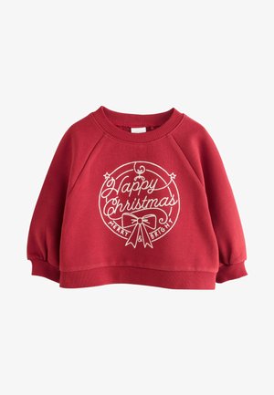Sarkans bērnu džemperis ar baltiem uzrakstiem "Priecīgus Ziemassvētkus, Mirdzošus un Laimīgus" un lentītes grafiku priekšpusē, ar ribotām aprocēm un apakšu.