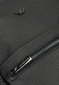 Czarna tkanina skórzana o teksturowanej powierzchni, z srebrnym zamkiem błyskawicznym i nazwą marki "wojos" wytłoczoną na metce.