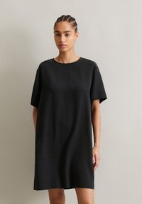 Black short-sleeve dress made of smooth fabric, featuring a round neckline and loose, relaxed fit. Simple, minimalist design without embellishments.
