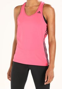 Różowy sportowy top na ramiączkach wykonany z lekkiego materiału, z czarnymi paskami po bokach i okrągłym dekoltem. Odpowiedni do uprawiania sportu i ćwiczeń.
