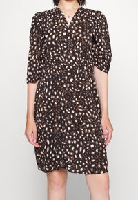 Svart klänning med korta puffärmar, med ett leopardmönster i brunt och krämfärgat. V-ringning och rynkad midjedetalj.