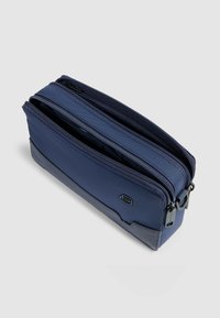 Bolsa azul marino con doble cremallera, fabricada en tela duradera, que presenta una base texturizada y una sección superior lisa con un detalle de logo minimalista.