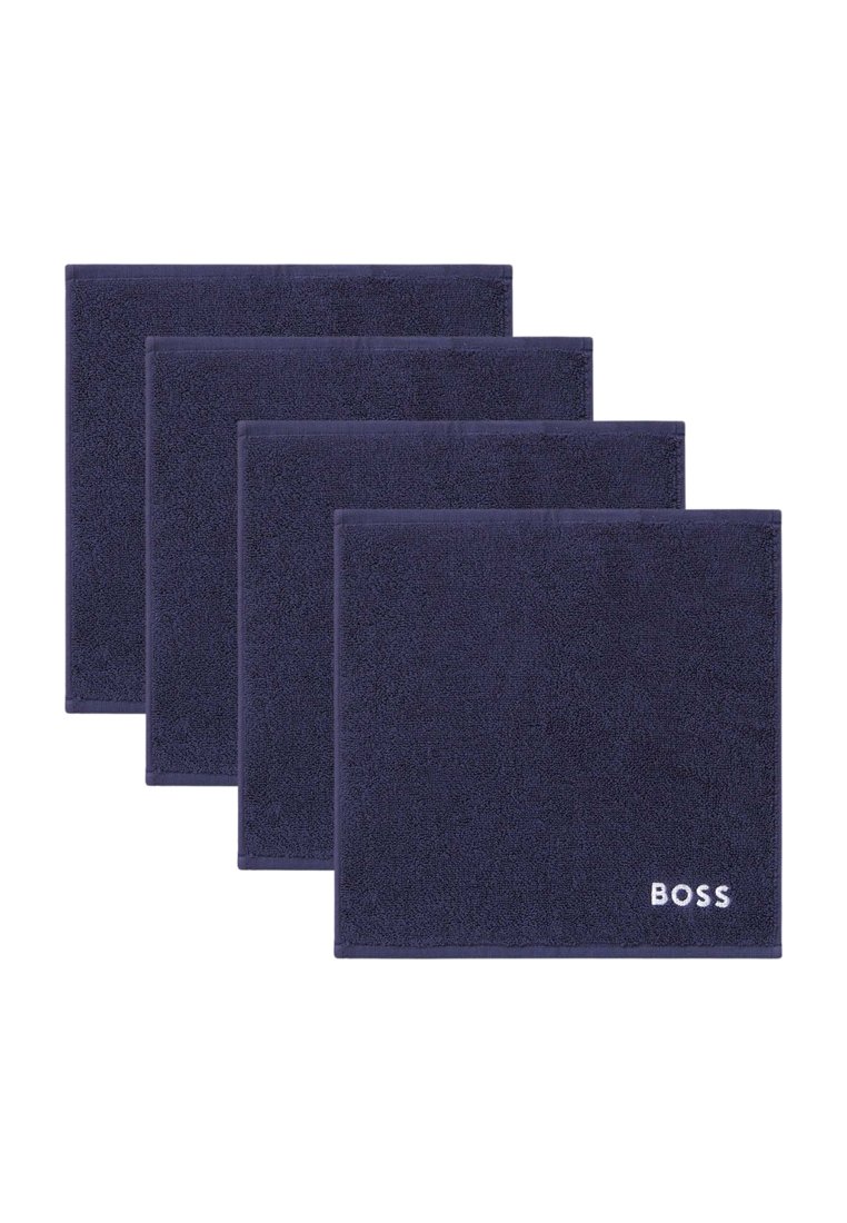 Ensemble de quatre tapis de bain bleu marine en tissu pelucheux, avec une surface texturée et le logo "BOSS" blanc dans un coin.
