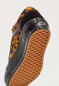 Soletta della scarpa con motivo a waffle, intersuola nera e tomaia con stampa leopardata, caratterizzata da una striscia bianca cucita e dal logo "Off The Wall" sul tallone.