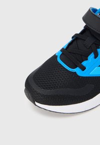 Μαύρο αθλητικό παπούτσι με επάνω μέρος από δίχτυ, μπλε λεπτομέρειες, μαύρα κορδόνια και λουράκι. Διαθέτει λευκή ενδιάμεση σόλα και υφή σόλας από καουτσούκ.