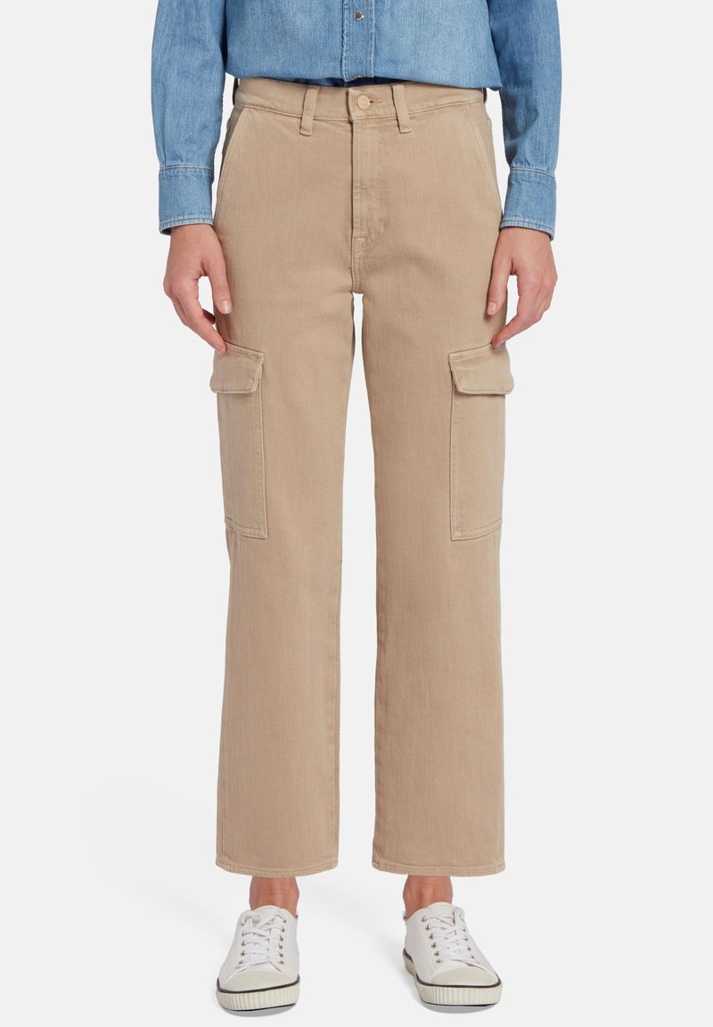 Beige cargobroek met een losse pasvorm, voorzien van twee zijzakken en een gladde textuur. Gepaard met witte sneakers en een denim shirt.