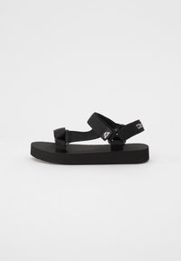 Svarta sandaler med tjock platt sula, justerbara nylonremmar och logotypdetaljer. Enkelt design utan mönster eller utsmyckningar.