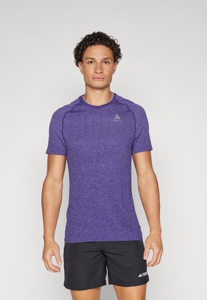 Purple athletic t-shirt with textured fabric, short sleeves, and a crew neckline, paired with black shorts featuring a logo accent.