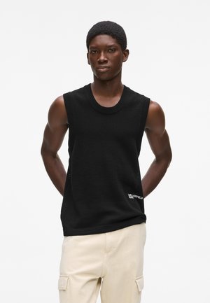 Fekete, ujjatlan kötött pulóver kerek nyakkivágással, bordázott szegélyekkel és egy kis fehér logóval az alsó bal oldalon.