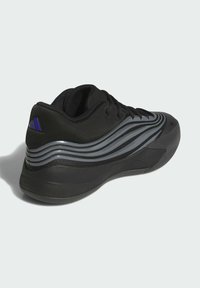 Chaussure de sport noire avec un dessus en tissu texturé, des rayures ondulées grises et une semelle en caoutchouc à profil bas avec un col rembourré.