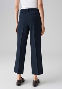 Pantalons large bleu marine avec une taille élastique, dotés de deux poches arrière et d'une finition en tissu lisse et texturé.