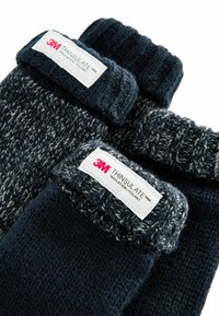 Pletené rukavice v námorníckej modrej a šedej farbe, so žebrovaným manžetom. Označenia zobrazujú "3M THINSULATE" pre izoláciu. Mäkký, textúrovaný povrch.