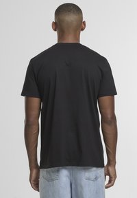 Zwarte katoenen T-shirt met korte mouwen en ronde hals, met een gladde textuur en een losse pasvorm, gezien van de achterkant.