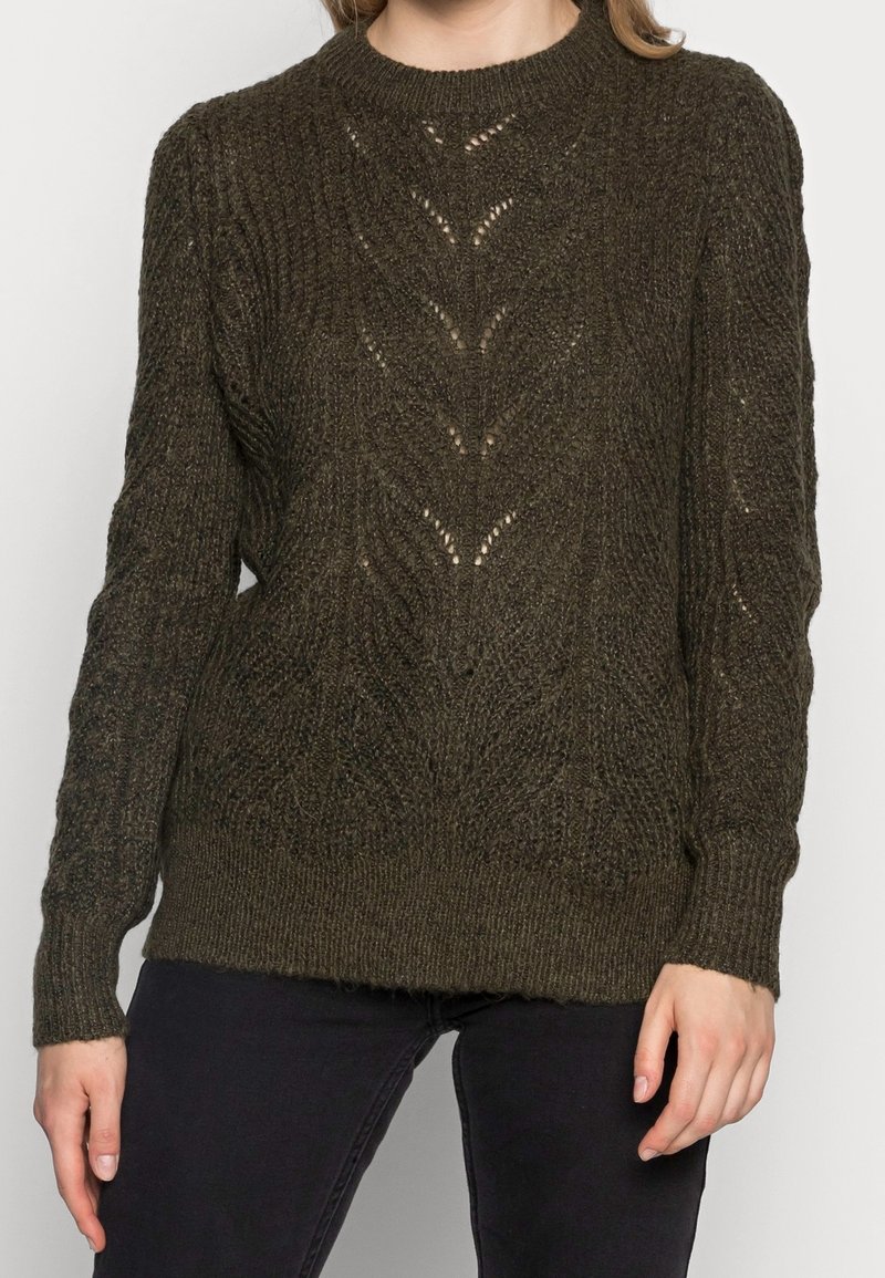 Pull en maille vert olive foncé avec motifs texturés, encolure ronde, poignets et ourlet côtelés, présentant des détails ajourés sur toute la surface.