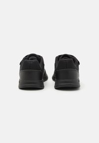 Chaussures de sport noires avec une tige en mesh, un col rembourré et une semelle en caoutchouc texturée avec des accents noirs lisses. Vue arrière affichée.