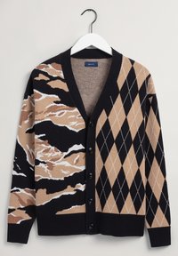 Kardigan med V-ringning, svart grundfärg, med ett beige, vitt och svart abstrakt mönster på ena sidan och ett rutigt mönster på den andra.