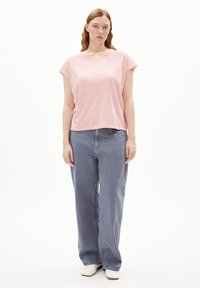 T-shirt à manches courtes rose et blanche à rayures, avec une coupe décontractée, associé à un jean large bleu clair et des bottines blanches.