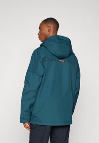 Veste imperméable teal avec capuche, doté d'un zip frontal, de poignets élastiques et d'une bande réfléchissante dans le dos.