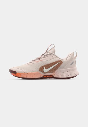 Nike Trail ATC sko i beige mesh med et tekstureret design. Har en brun sål, en orange spottet mellemsål og et fremtrædende Swoosh-logo.