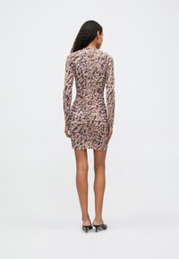 Rjavica z dolgimi rokavi v roza in bež barvi z abstraktnimi vzorci, ki ima naborke na hrbtu in oprijet silhueto, ki se konča nad kolenom.