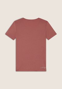 Camiseta de manga corta y cuello redondo en color rosa polvo, hecha de una tela suave con una sutil textura, que presenta un pequeño logotipo en la esquina inferior.
