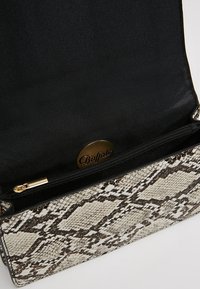 Borsa a mano rettangolare con motivo a stampa serpente in tonalità di beige e marrone. Interno nero con tasca con zip e dettagli in hardware dorato.