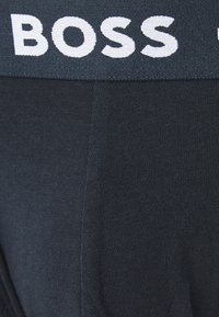 Fekete pamut boxer alsónadrág bordázott textúrával és széles, fehér "BOSS" logót feltüntető derékkal rendelkezik.