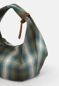 Strukturierte Stofftasche mit einem karierten Muster in Blau, Grün und Weiß, einer geschwungenen, weichen Form und braunen Lederakzenten am Griff.