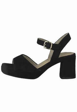 Sandales en suède noir à talon bloc avec un bout ouvert et une bride de cheville dotée d'une boucle en ton doré. La semelle est plus épaisse pour un confort accru.
