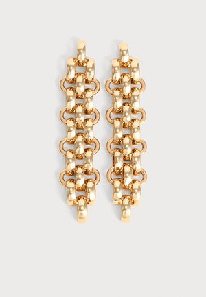 Paire de boucles d’oreilles pendantes en chaîne dorée avec alternance de grands maillons arrondis et de petites boucles circulaires sur fond clair.