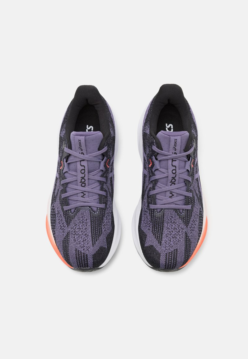 Lila Sport Schuhe mit einem strukturierten Strick-Obermaterial, schwarzen Akzenten und einer weißen Zwischensohle mit einem orangefarbenen Detail an der Ferse.