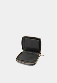 Portefeuille en cuir noir avec fermeture éclair, comprenant des emplacements pour cartes et une poche transparente pour ID. Fermeture éclair et accents en ton doré.