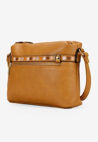 Bolso cruzado de cuero marrón claro con un compartimento con cremallera, que presenta un patrón decorativo de flores y una correa desmontable. Textura suave, forma compacta.
