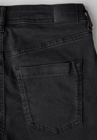 I jeans di denim neri presentano una tasca posteriore rettangolare e un'etichetta in pelle in vita. La texture è liscia con dettagli di cucitura sottili.
