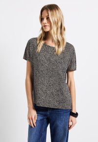 Top a maniche corte in design animalier nero e beige. Realizzato in tessuto leggero con una vestibilità comoda e scollo rotondo.