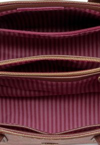 Interieur van een bruine leren handtas met drie compartimenten, gevoerd met bordeauxrode stof met verticale strepen, en gouden ritssluitingen.