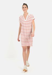 Gestreiftes Kleid in Weiß und Koralle, aus weichem Stoff gefertigt. Mit einem Kragen, kurzen Ärmeln und seitlichen Schlitzen für Bewegungsfreiheit.