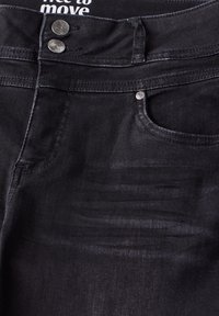 Černé denimové džíny s hladkým povrchem, které mají zapínání na knoflík, dvě přední kapsy a viditelné švy.