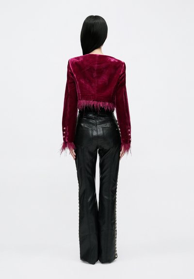 Burgundi sametist lühike jakk, millel on ääres tuttidega kaunistus, ühendatud mustade nahast kõrge vöökohaga pükstega, millel on külgedel nupud.