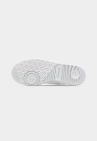 Zool van een witte sneaker met ronde grip-patronen, getextureerde lijnen en het "TRETORN"-logo zichtbaar op de rubberen buitenzool.