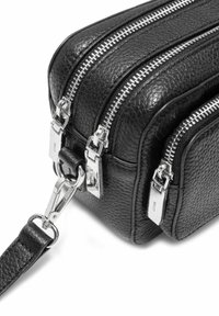 Czarna skórzana torba z teksturowaną powierzchnią, dwoma zasuwanymi komorami, srebrnym okuciem i odczepianym paskiem.